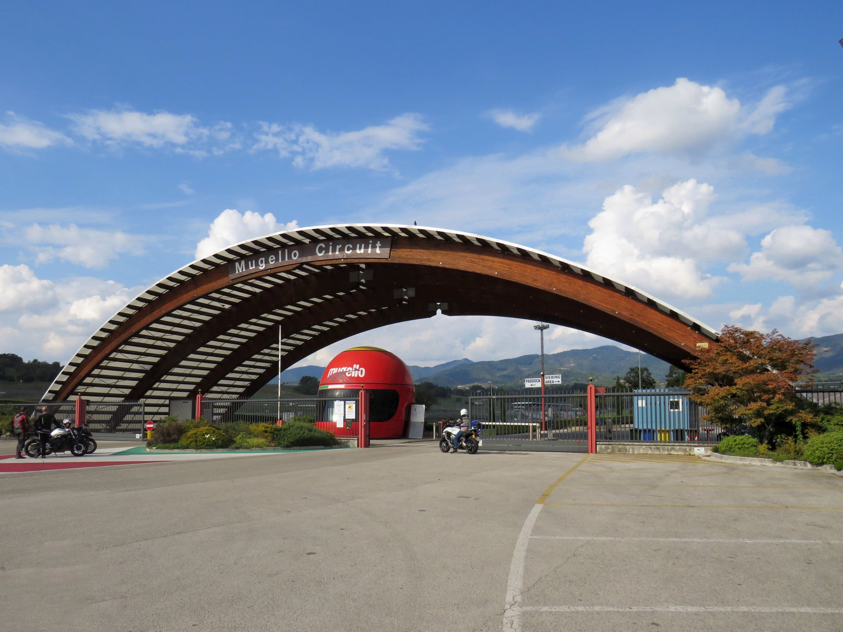 Arche en bois de l'entrée du circuit du Mugello et casque géant, motards et montagnes en arrière-plan