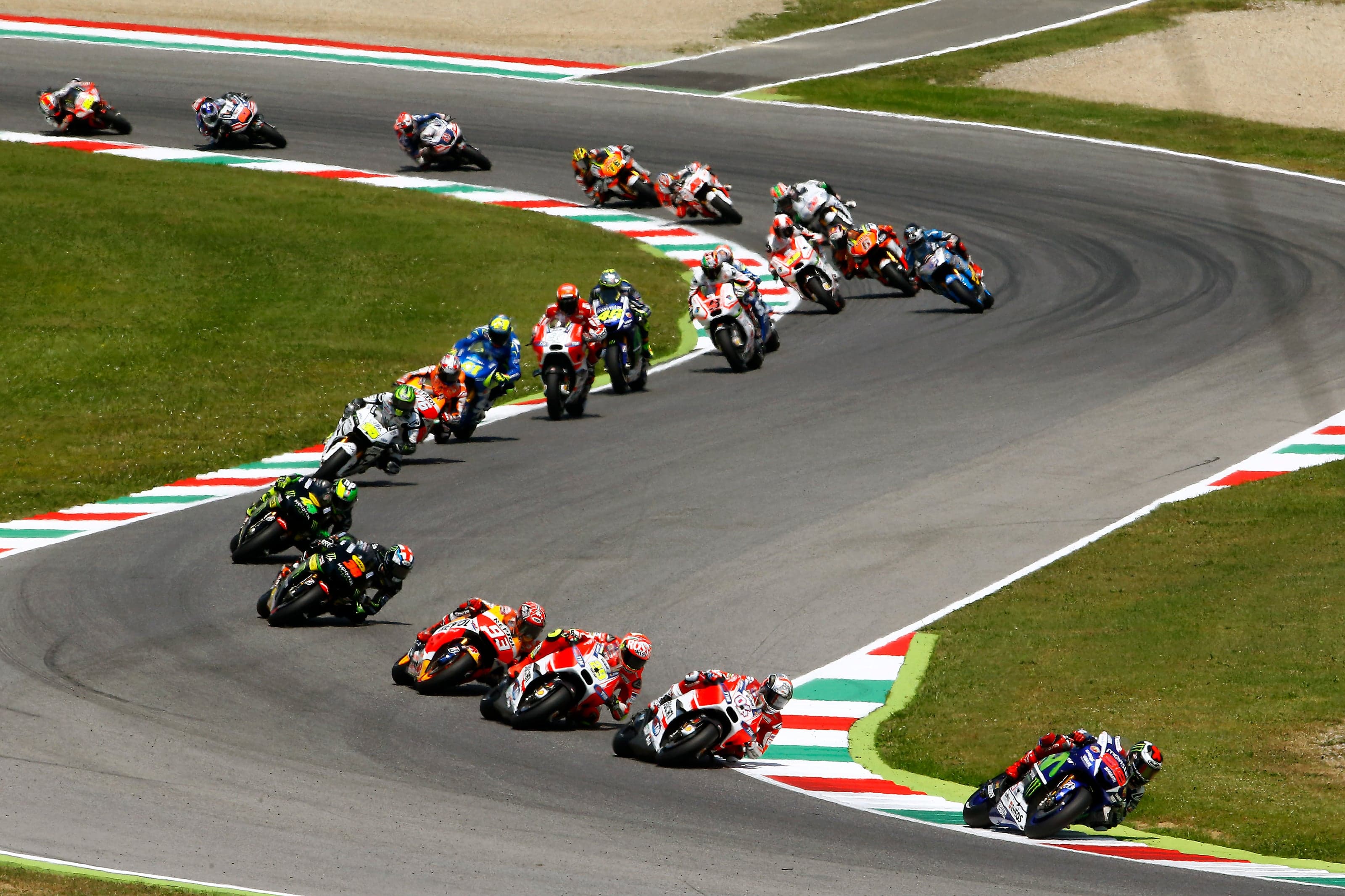 Peloton de MotoGP dans un enchaînement aux vibreurs tricolores du circuit du Mugello